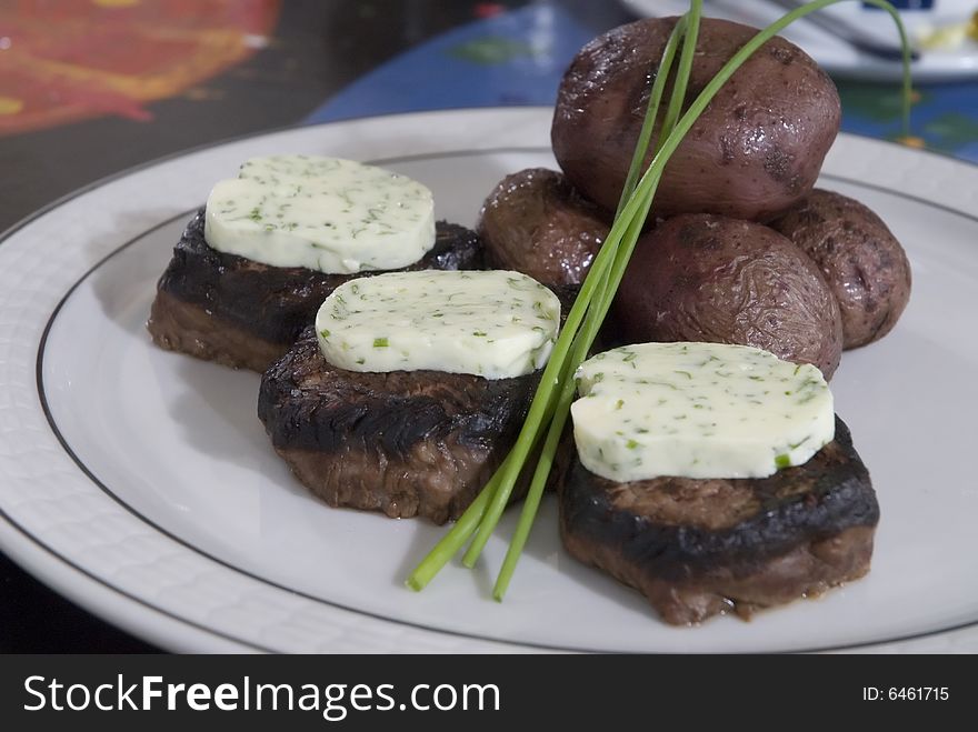 Steak medallions with herb butter and baked potatoes. Steak medallions with herb butter and baked potatoes