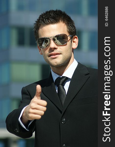 Portrait of a young man with highly successful stretched thumb and sunglasses. Portrait of a young man with highly successful stretched thumb and sunglasses