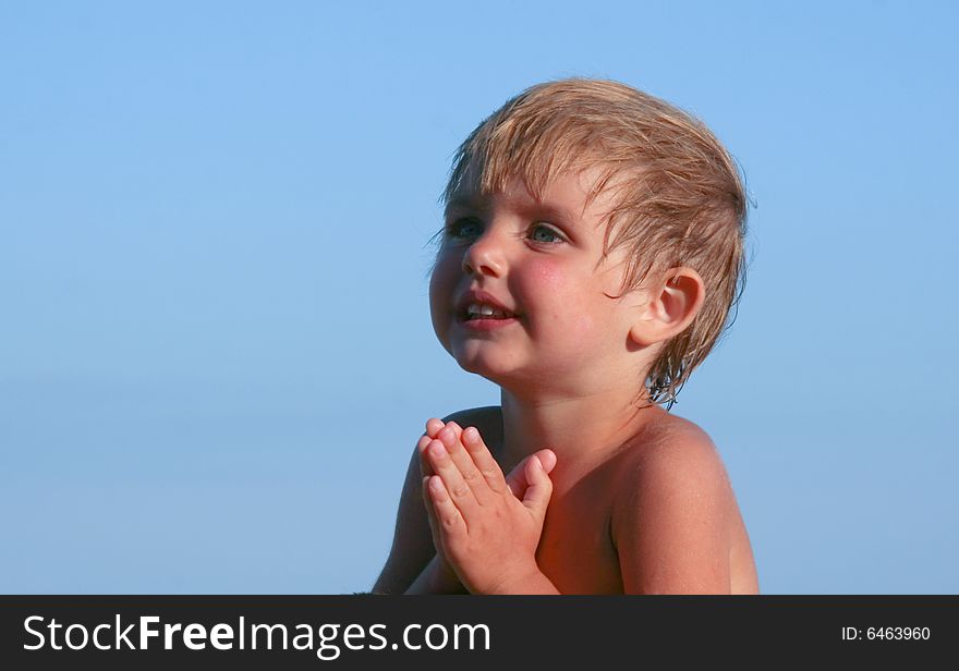 The little girl prays against the dark blue sky