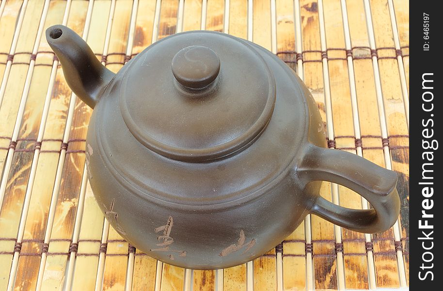 Classic chinese teapot of brown clay over bamboo mat