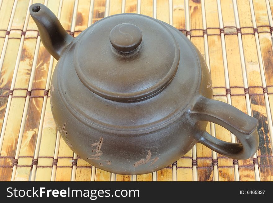 Classic chinese teapot of brown clay over bamboo mat