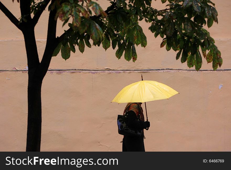 Woman walking with a yellow umbrella