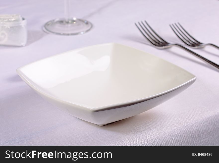 White china bowl in an elegant restaurant place setting. White china bowl in an elegant restaurant place setting