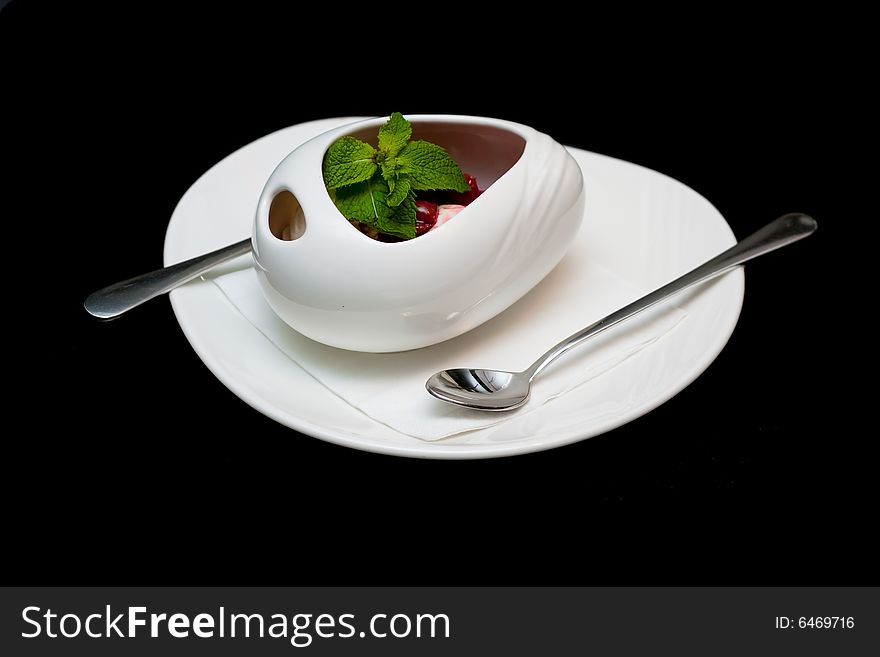 Japanese rice ice-cream with cherry-ginger compote in white cup isolated on black