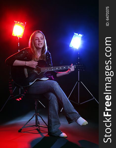 Woman with guitar on stage with red and blue concert lights. Woman with guitar on stage with red and blue concert lights