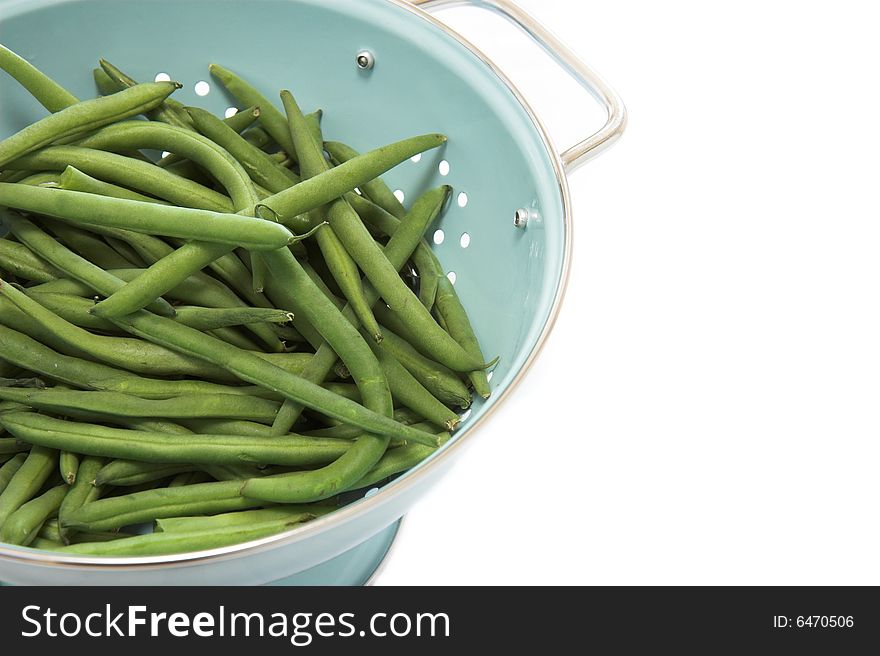 A blue colander full of green beans, isolated on white. A blue colander full of green beans, isolated on white.