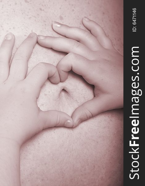 Little girl making a heart out of her fingers on mommy pregnant belly