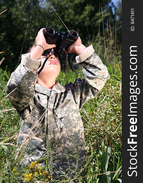Boy in camouflage jacket looking up through binoculars