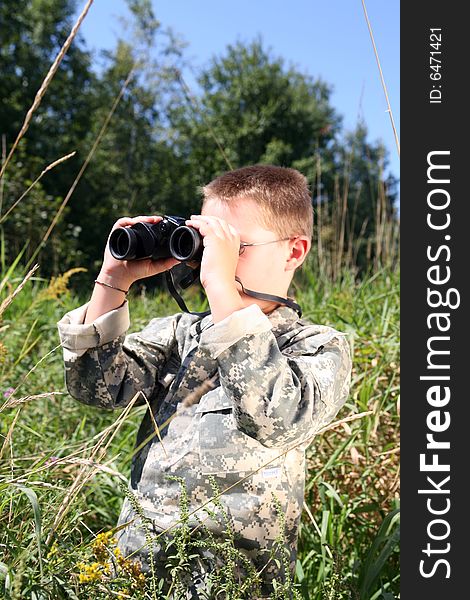 Young boy looking through binoculars in a field