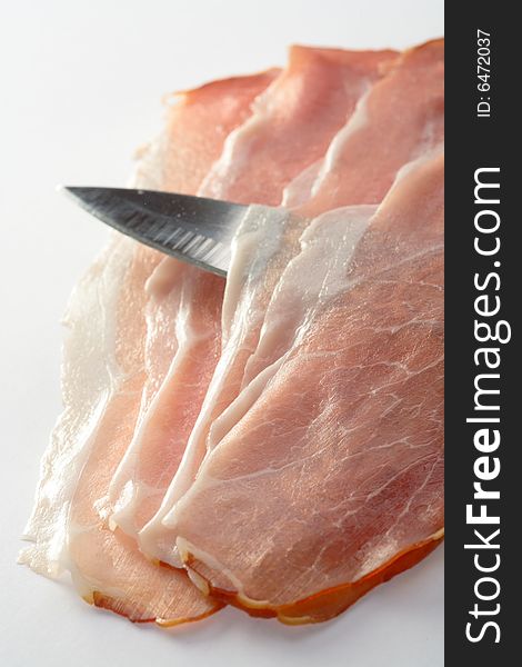 Slices of ham and knife on the white background. Slices of ham and knife on the white background