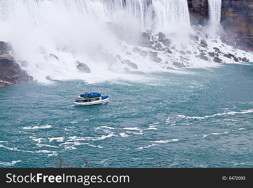 A boat sailing in a river next to Niagara falls. A boat sailing in a river next to Niagara falls