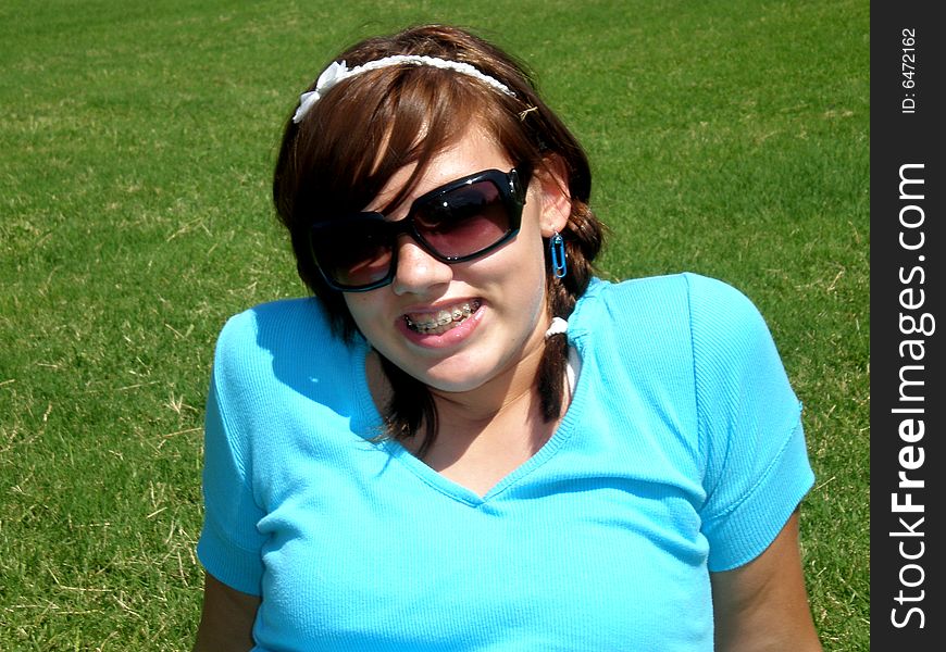 A picture of a young teenage girl smiling and sitting in the grass. A picture of a young teenage girl smiling and sitting in the grass.