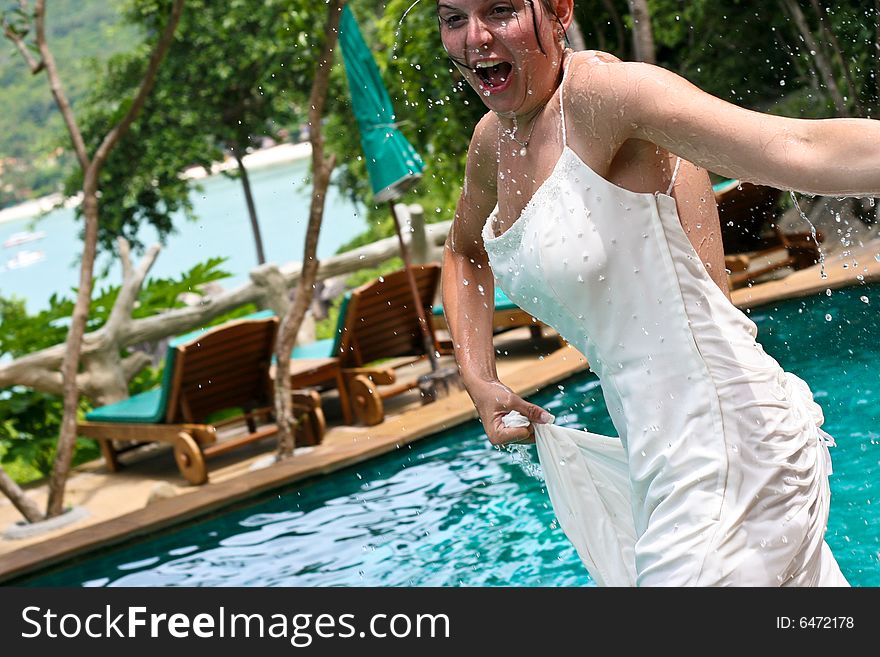 Tropical bride gets pushed into the pool on her wedding day. Trash the dress trend.