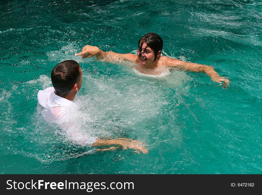 Bride and groom celebrating their wedding day by jumping in a swimming pool. Bride and groom celebrating their wedding day by jumping in a swimming pool.