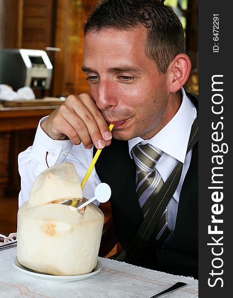 Businessman drinking from a coconut.