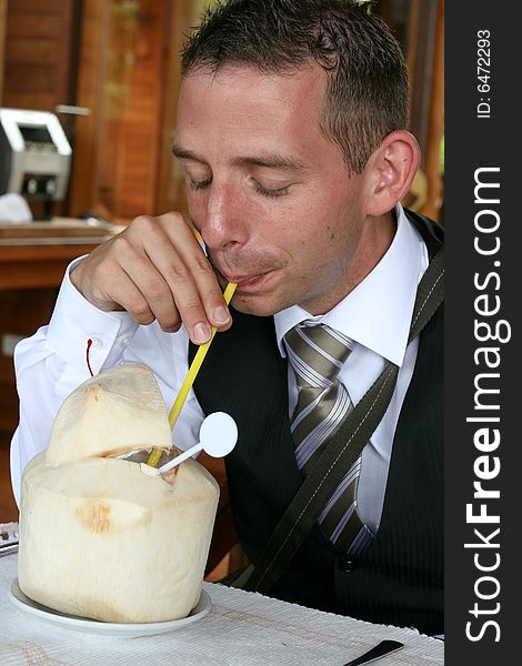 Businessman drinking from a coconut.