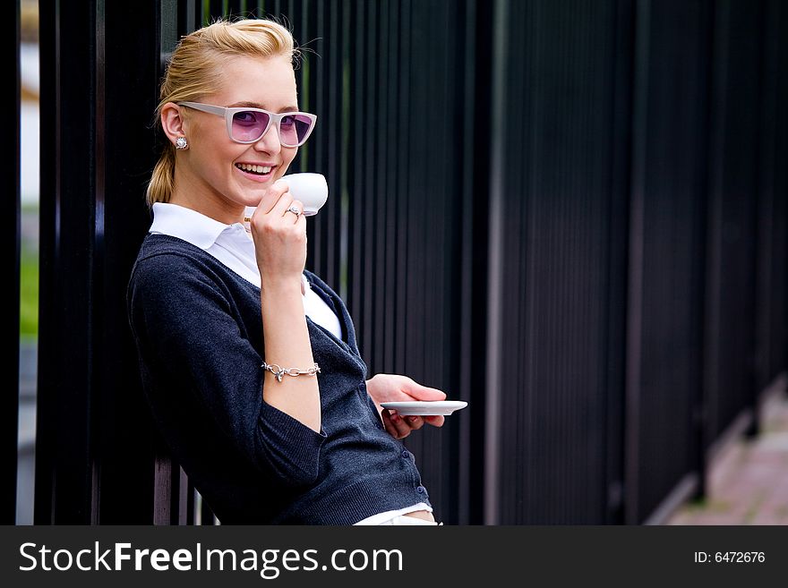 Smiling lovely young woman drinking coffee outside. Smiling lovely young woman drinking coffee outside