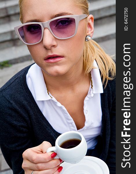 Blond lovely young woman drinking coffee outside. Blond lovely young woman drinking coffee outside