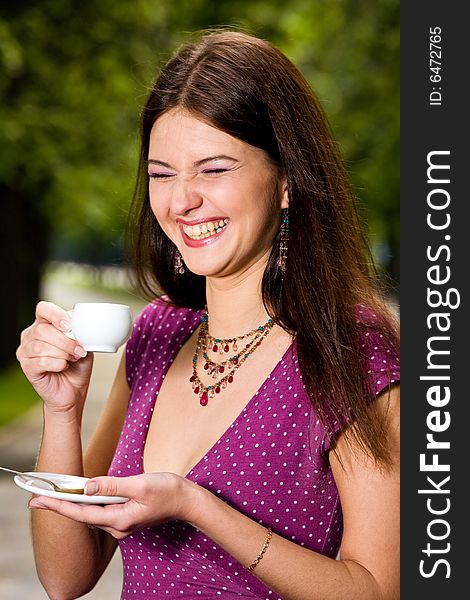 Laughing lovely young woman drinking coffee outside. Laughing lovely young woman drinking coffee outside