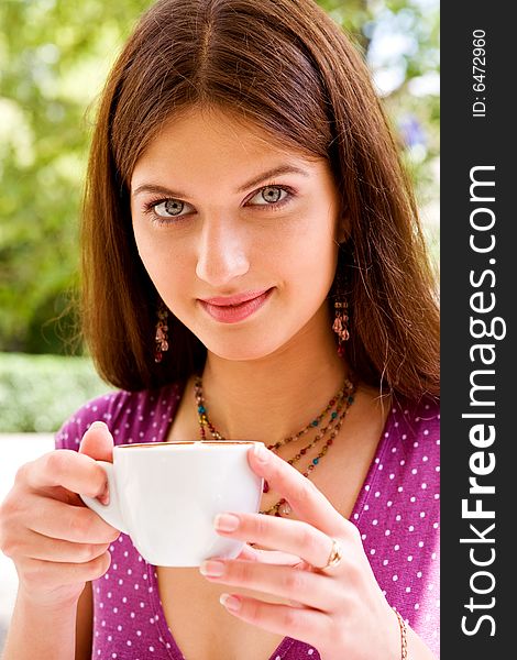 Smiling lovely young woman drinking coffee outside. Smiling lovely young woman drinking coffee outside