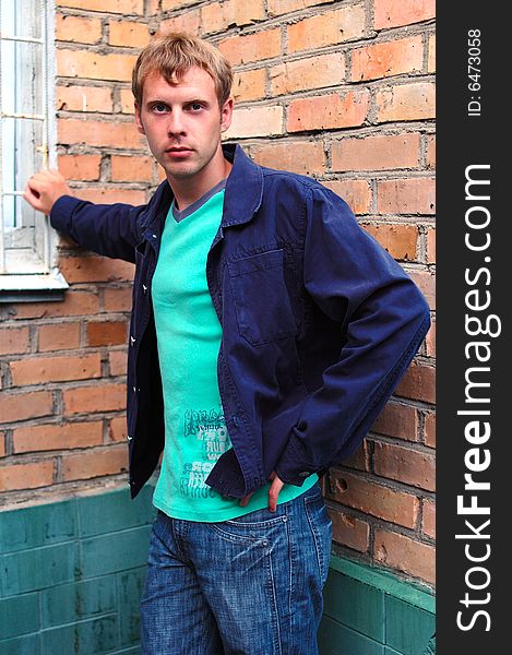 Young stylish man with blonde hair stand near brick wall. Young stylish man with blonde hair stand near brick wall.