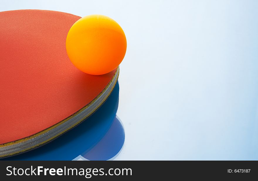 Tennis racket and orange ball on a blue background