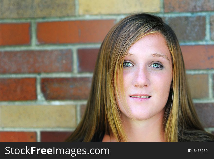 A green eyed woman standing in front of a wall. A green eyed woman standing in front of a wall