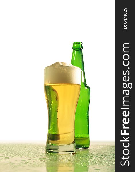 Glass of light beer and green bottle standing on white background. Glass of light beer and green bottle standing on white background