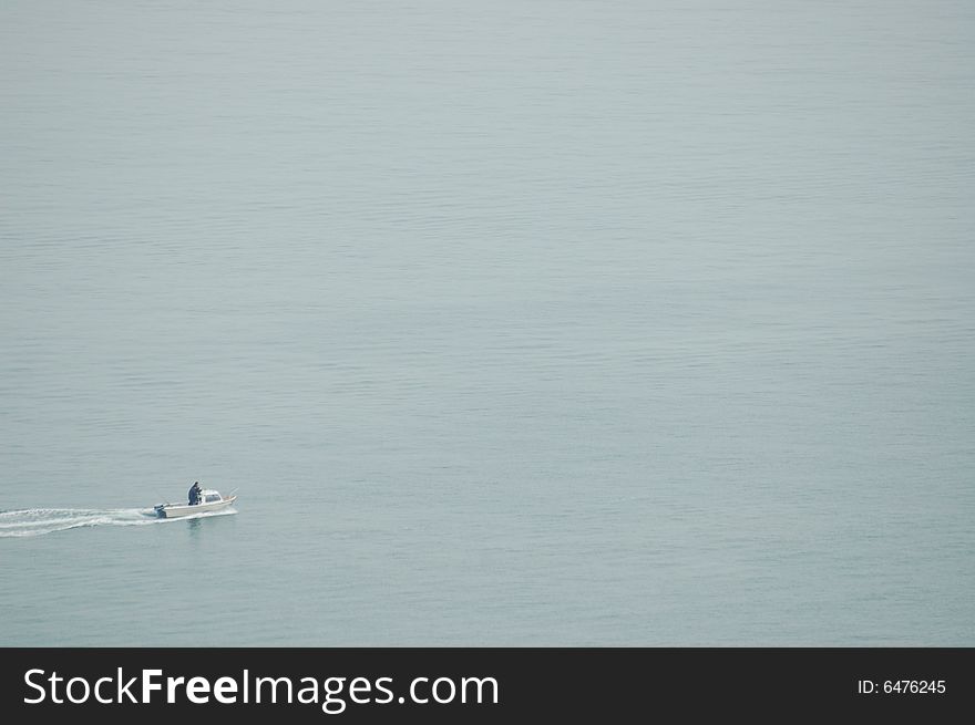 A Small fishing or leisure boat crossing some very still water. A Small fishing or leisure boat crossing some very still water