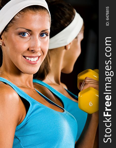 Attractive young woman curling a dumbbell with a happy smile. Attractive young woman curling a dumbbell with a happy smile