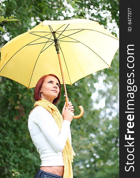 Beautiful young girl under yellow umbrella