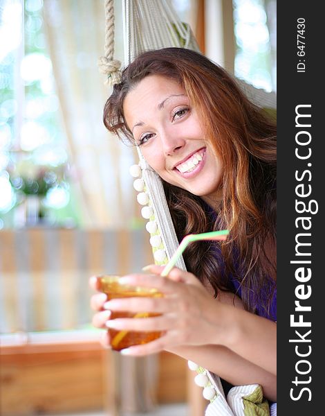 Happy long-haired girl drinking lemonade in comfortable cottage