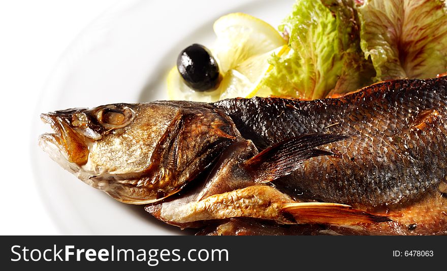 Fish Baked in Spicy Served with Salad Leaves, Lemon and Olives. Isolated on White Background. Fish Baked in Spicy Served with Salad Leaves, Lemon and Olives. Isolated on White Background