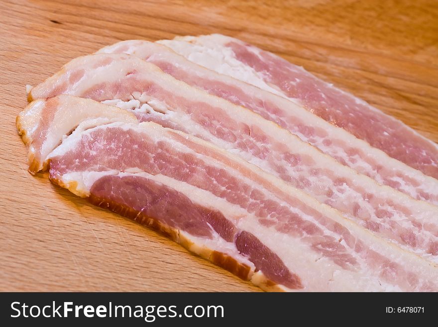 Sliced raw bacon on a wood cutting board