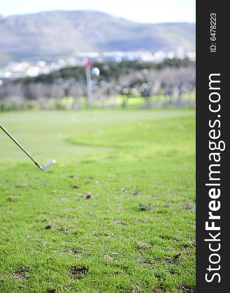 Conceptual shot of a golfer in action on a practice range, hitting the ball with a club. Focus is on the impact point where the club hit the ball.