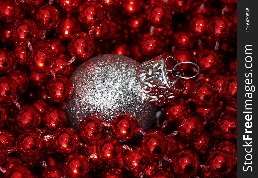 Silver christmas bauble on a bed of red beads. Silver christmas bauble on a bed of red beads