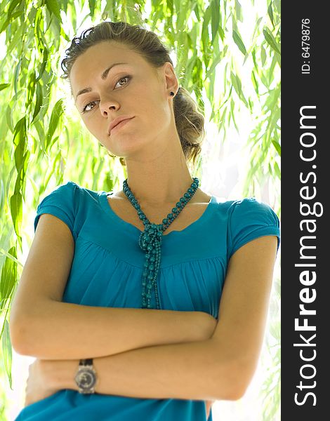 Beautiful woman with blue beads near willow. Beautiful woman with blue beads near willow