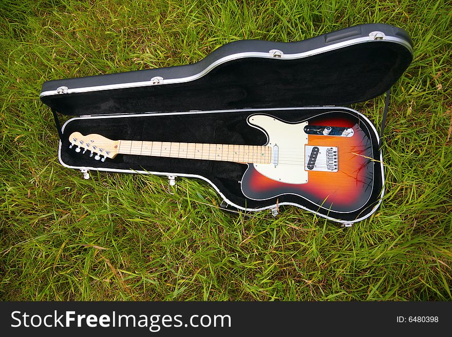 Guitar in case on green grass. Guitar in case on green grass