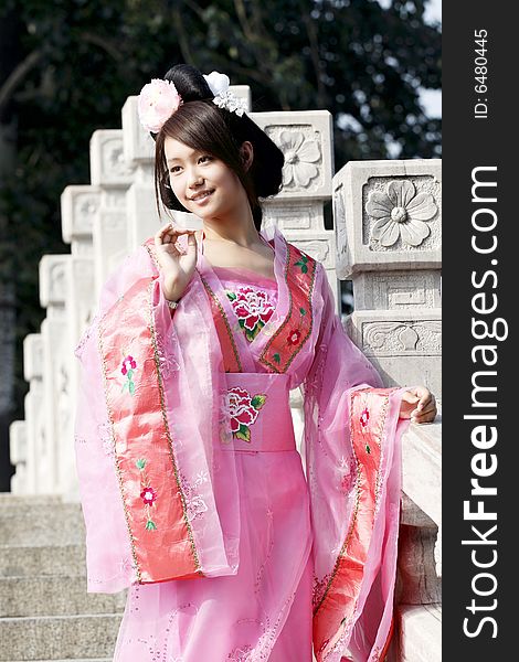 A girl in Chinese ancient dress. She is standing on the ancient bridge.She is so beautiful and lovely. A girl in Chinese ancient dress. She is standing on the ancient bridge.She is so beautiful and lovely.