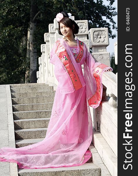 A girl in Chinese ancient dress. She is standing on the ancient bridge.She is so beautiful. A girl in Chinese ancient dress. She is standing on the ancient bridge.She is so beautiful.