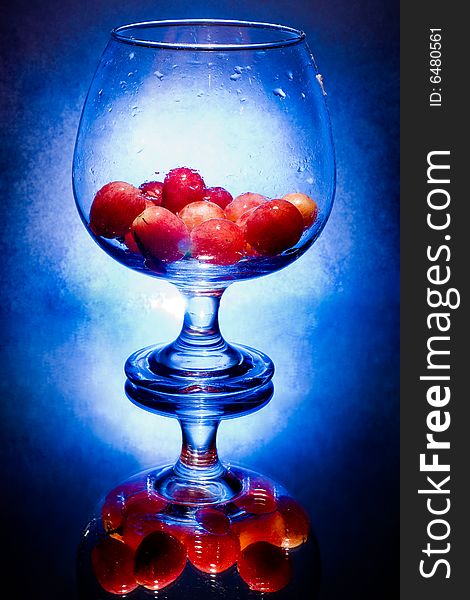 Glass full of water with fresh grapes on blue background. Glass full of water with fresh grapes on blue background