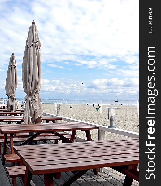 Wooden tables and umbrellas in outside restaurant with sea view.