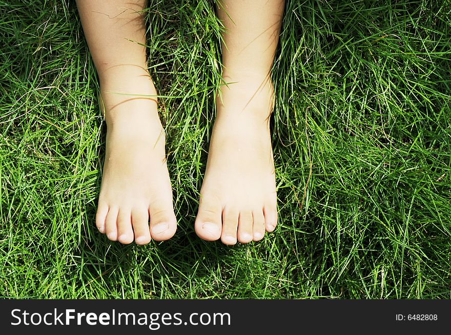 The feet of a little boy on the meadow in the garden. The feet of a little boy on the meadow in the garden.