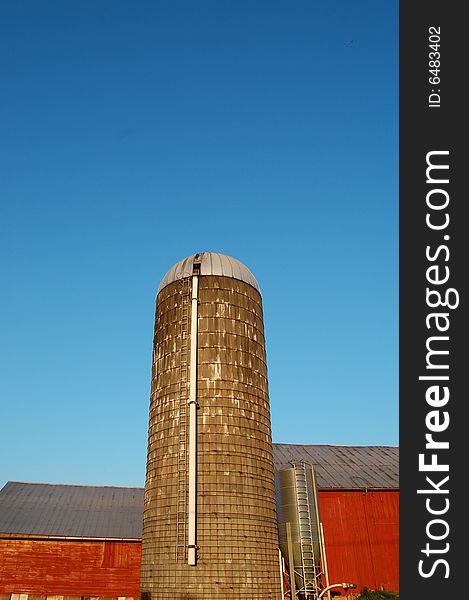 Silo with red barn against intense blue sky