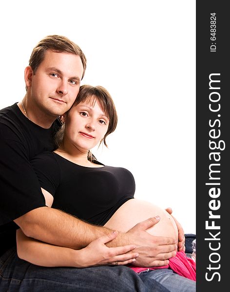 Young man and his pregnant wife embracing isolated against white background