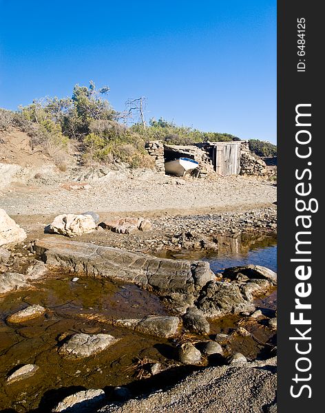 Boat in a shed on a rocky beach.