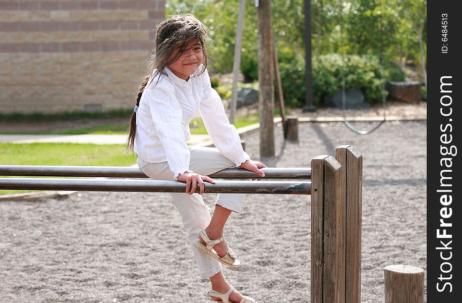 Little girl sitting on top of parallel bars at playground. Little girl sitting on top of parallel bars at playground