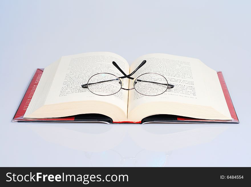 Open book with a pair of eye glasses on top