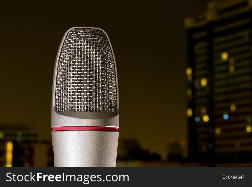 Microphone in front of a city skyline at night