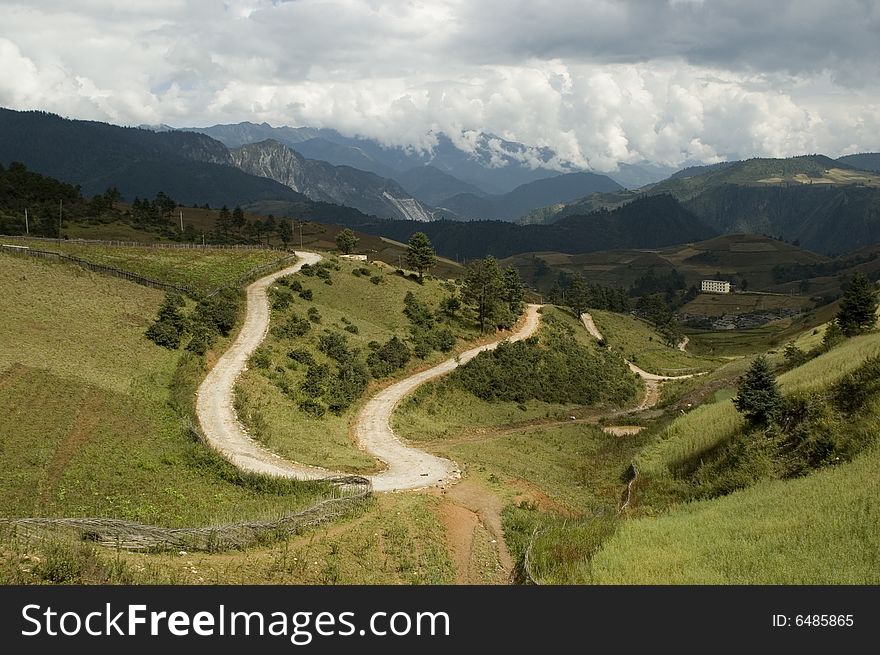 Yunnan province, China - beautiful landscape - roads, trees, meadows and high mountains surrounding village. Yunnan province, China - beautiful landscape - roads, trees, meadows and high mountains surrounding village.